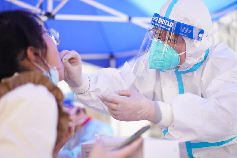 進入小區一律戴口罩、量體溫及檢查健康碼。(新華社)