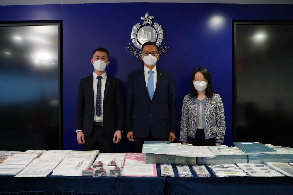 商業罪案調查科署理警司陸振中(中)、商業罪案調查科高級督察羅奕鵬(左)及香港按證保險有限公司副總裁莫愛蘭(右)展示行動中檢獲的證物。(警方圖片)