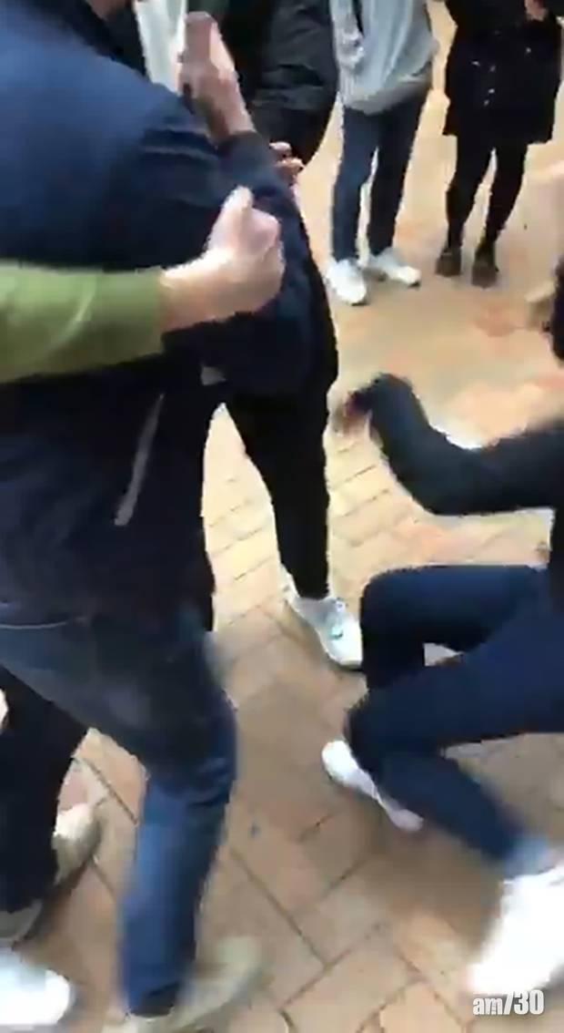 其中一名中國學生用手臂推撞香港女學生,那女學生跌倒在地。