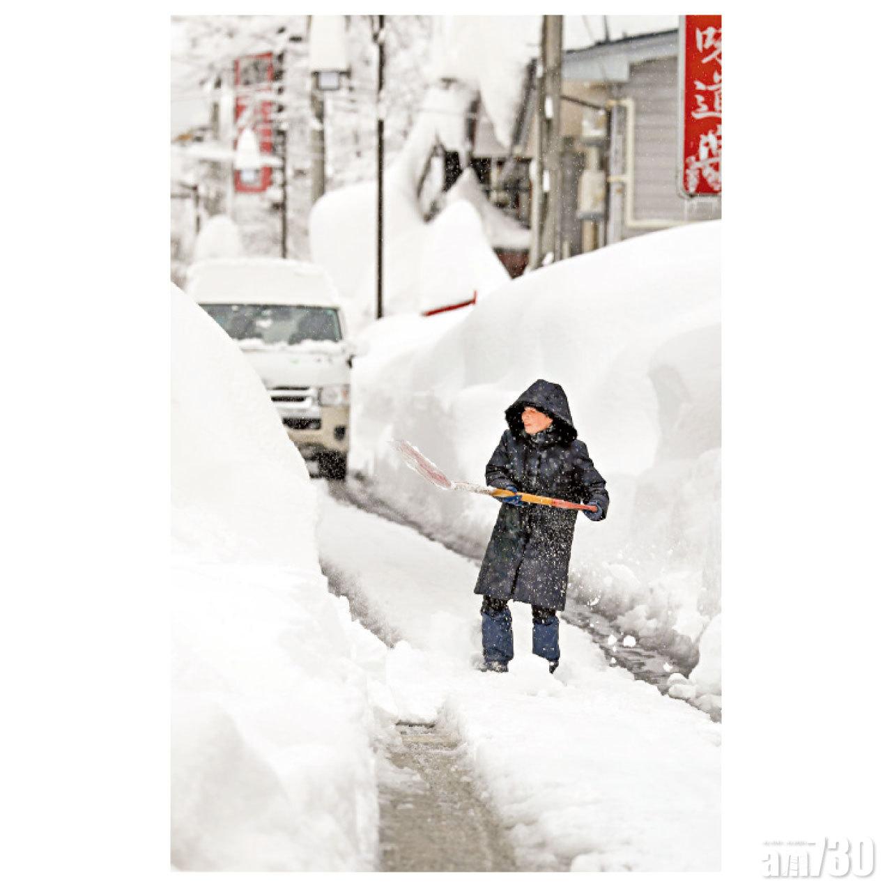 新潟縣湯澤町一名女居民上周四在街上清除積雪。(路透社)