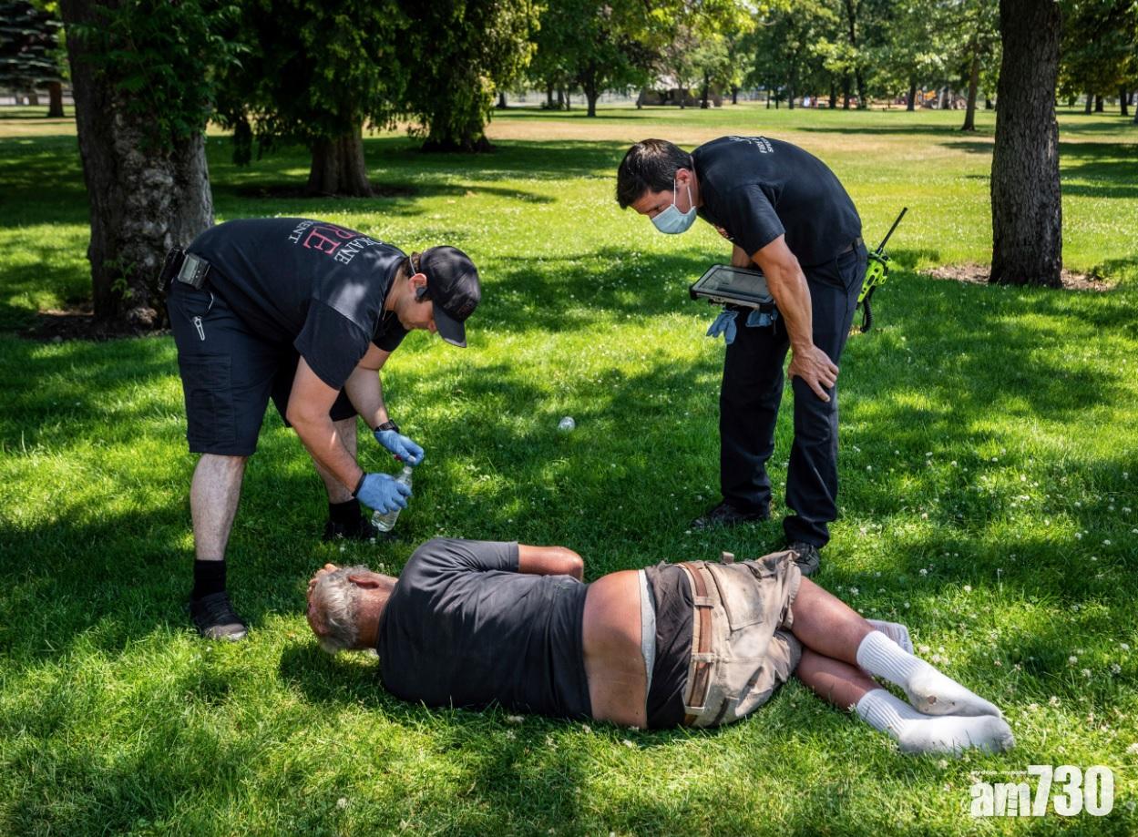 美國華盛頓州Spokane熱到38度, 一名男子在戶外感不適,消防員幫他降溫。(美聯社)